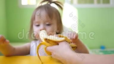 妈妈在<strong>厨房</strong>的桌子旁喂小香蕉。 为<strong>幼儿</strong>补充.. 可爱的零食小子